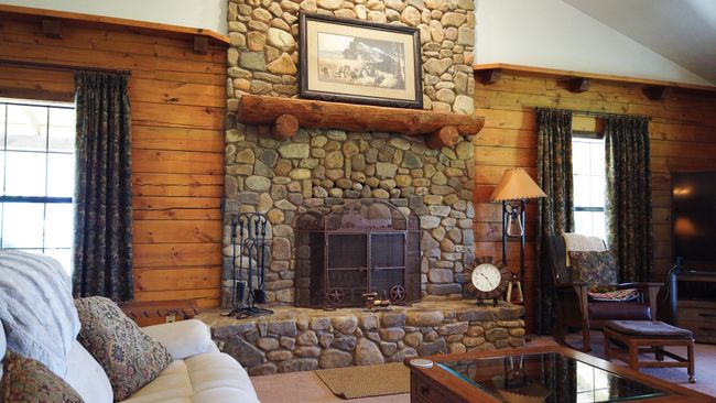 Carpeted living room with wooden walls, a fireplace, and vaulted ceiling | Image 11