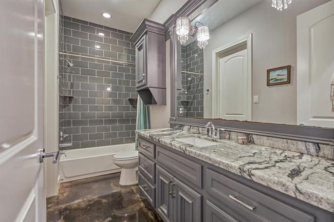 A spacious full bath serves the first bedroom and also offers convenient access from the hallway for guests. High-end finishes are showcased throughout, including custom molding around the mirrors, designer lighting, granite countertops, coordinating millwork, and exquisite tilework in the shower. | Image 11