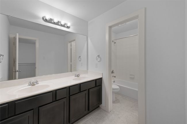 Full bathroom with double vanity, tile patterned floors, and shower / tub combination | Image 32