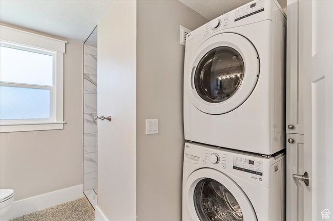 Washroom featuring stacked washer / drying machine and a textured ceiling | Image 33