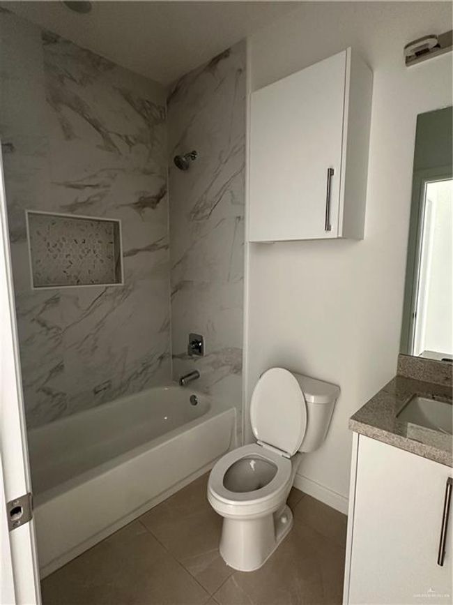 Bathroom with toilet, shower combination, tile patterned flooring, baseboards, and vanity | Image 10