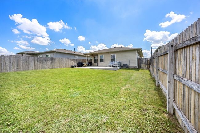 A different perspective of the backyard, showcasing the covered patio and the ample space for outdoor activities and entertaining. | Image 25