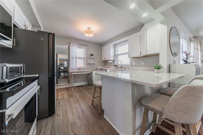Kitchen with a kitchen breakfast bar, dark wood finished floors, a sink, white cabinets, and a peninsula | Image 13