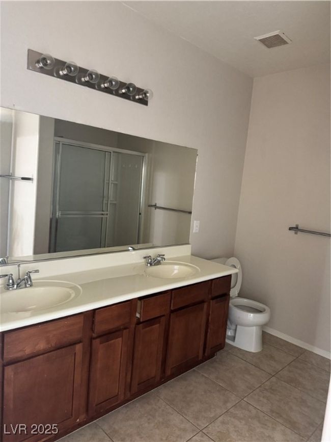 Bathroom featuring double vanity, tile patterned floors, and a shower with shower door | Image 13
