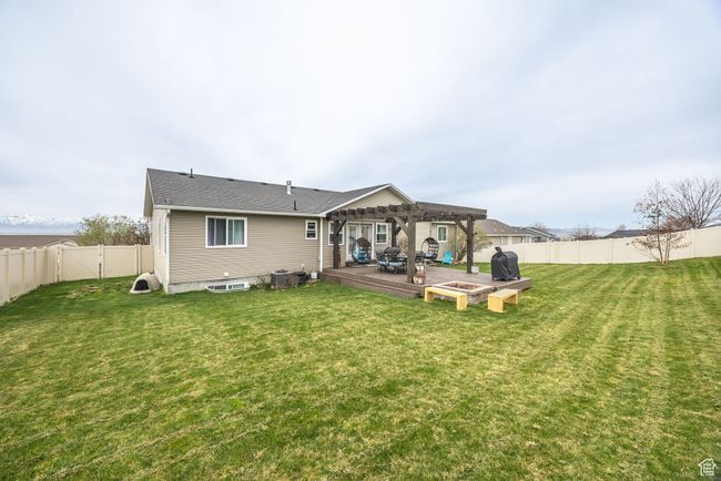 Rear view of property featuring a pergola, a lawn, a fenced backyard, and a deck | Image 37