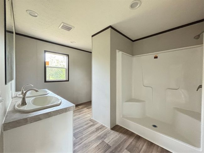 Full bathroom featuring vanity, wood look finished floors, crown molding, a shower, and a textured ceiling | Image 8