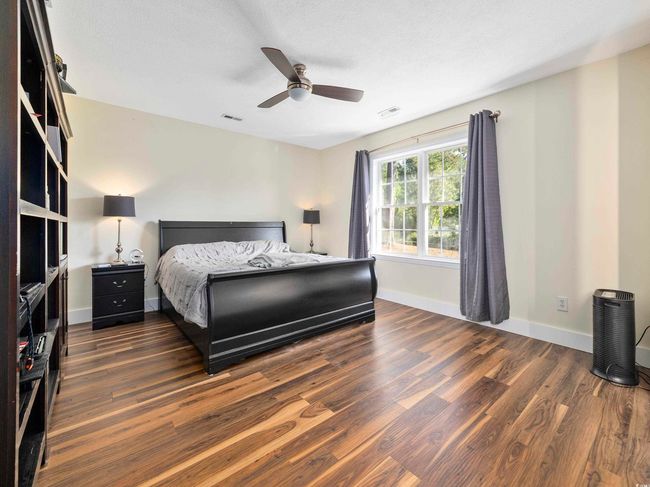 Bedroom with baseboards, a ceiling fan, dark wood finished floors, and visible vents | Image 16