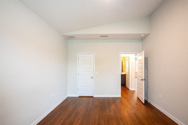 Unfurnished bedroom featuring visible vents, baseboards, vaulted ceiling, and dark wood-style floors | Image 12