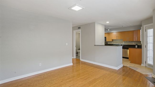 Kitchen featuring dark countertops, light wood-style flooring, dishwasher, baseboards, and a sink | Image 7