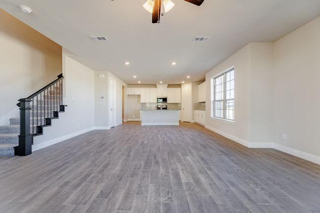 Unfurnished living room with light wood-style floors, a ceiling fan, stairs, and recessed lighting | Image 8
