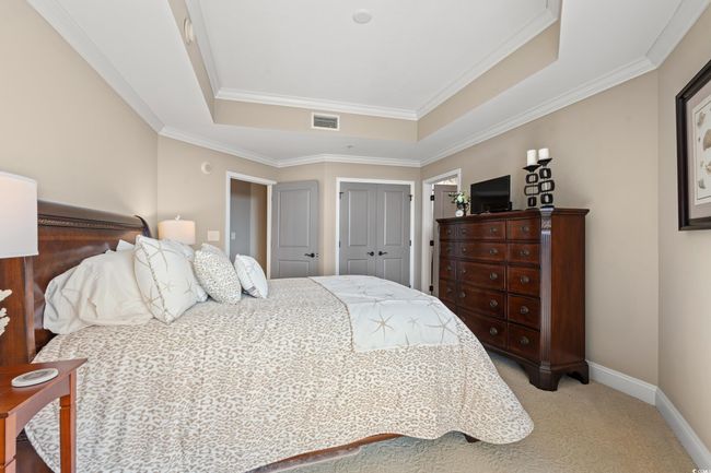 Bedroom featuring a tray ceiling, light colored carpet, a closet, and ornamental molding | Image 23