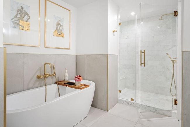 Gorgeous marble bathroom with dual-vanities, a soaking tub, and stunning gold finishes. | Image 21