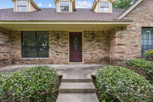 Doorway to property featuring a porch, brick siding, and a shingled roof | Image 4
