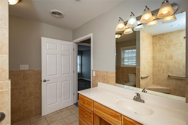 Bathroom featuring tile patterned flooring, visible vents, toilet, vanity, and tile walls | Image 30