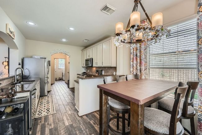 Kitchen with arched walkways, dark wood-type flooring, dark countertops, backsplash, and recessed lighting | Image 16