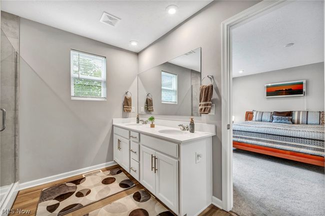 Bathroom featuring a healthy amount of sunlight, wood-type flooring, double vanity, and a shower with door | Image 35