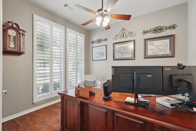 Bedroom currently set up as a Home office with a ceiling fan, dark wood-style floors, and baseboards | Image 4
