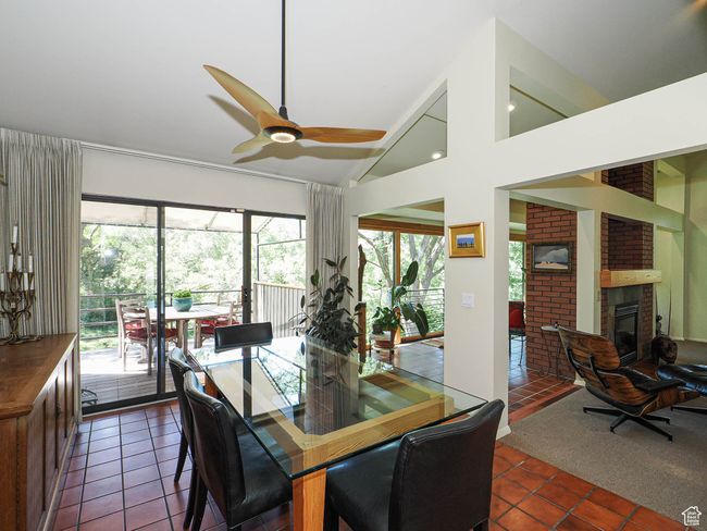 Dining room featuring dark tile patterned flooring, a ceiling fan, a fireplace, and high vaulted ceiling | Image 14