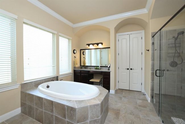 Soaker tub with tile surround. Vanity with makeup area and seating and large mirrors. | Image 27