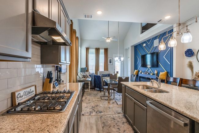 Kitchen featuring stainless steel appliances, a sink, exhaust hood, light stone countertops, and tasteful backsplash | Image 7