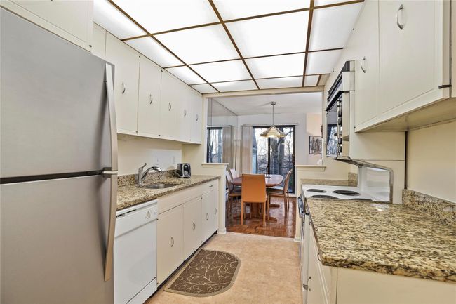 Kitchen with white appliances, white cabinets, and hanging light fixtures | Image 13