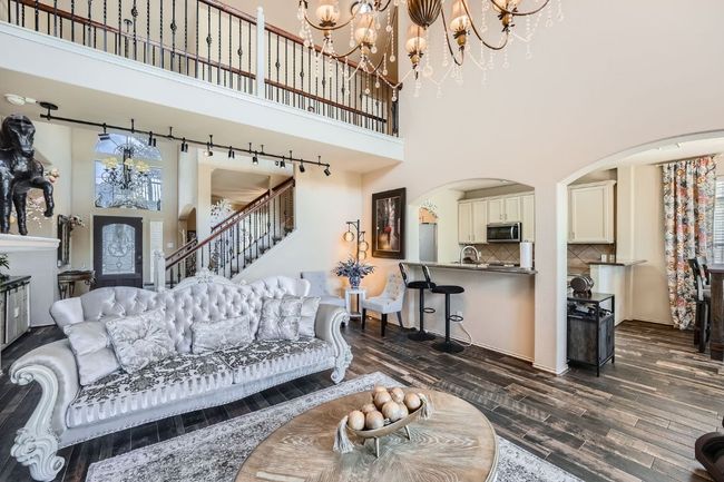 Living room featuring a towering ceiling, a chandelier, arched walkways, dark wood-type flooring, and stairway | Image 9