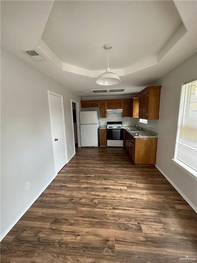 Kitchen featuring a tray ceiling, dark wood-type flooring, range with electric cooktop, and freestanding refrigerator | Image 13