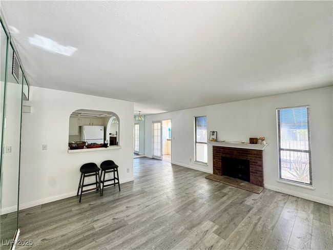 Living area with a textured ceiling, wood finished floors, a brick fireplace, and arched walkways | Image 5