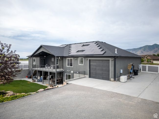 View of front of house featuring a garage, solar panels, driveway, stairway, and roof with shingles | Image 86