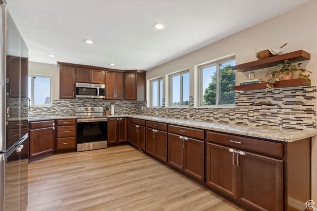 Kitchen with appliances with stainless steel finishes, granite countertops, wood LVP floors, recessed lighting, windows and backsplash | Image 9