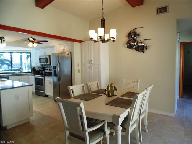 Dining area with baseboards, visible vents, lofted ceiling with beams, and ceiling fan with notable chandelier | Image 11