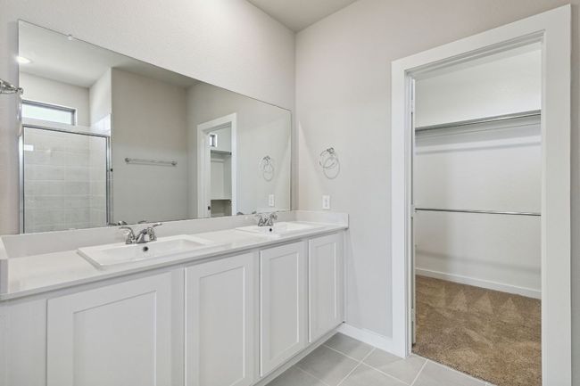 Full bath with a walk in closet, tiled shower, tile patterned flooring, and double vanity | Image 17