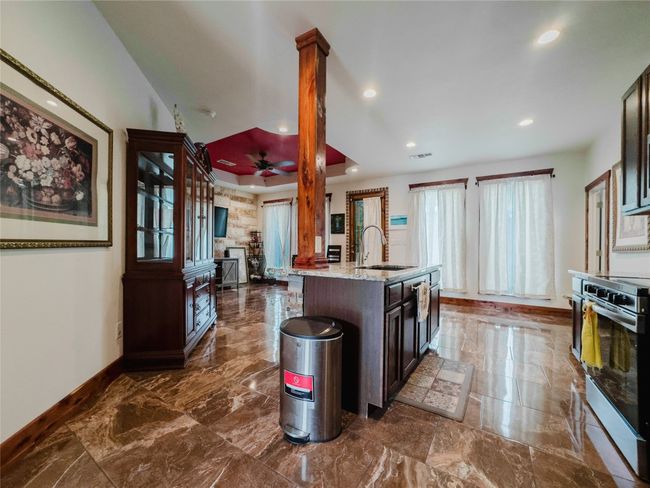 Kitchen featuring stainless steel range, recessed lighting, light stone countertops, dark marble finish floors, and dark brown cabinets | Image 10