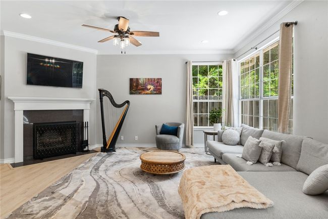 The living room is enhanced with upscale crown molding, LED recessed lighting, and a traditional wood-burning fireplace that provides comfort and warmth during the wintertime. | Image 4