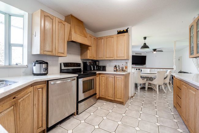 Kitchen with decorative backsplash, ceiling fan, stainless steel appliances, light countertops, and premium range hood | Image 14