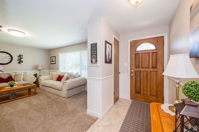 Entryway with a textured ceiling, light tile patterned floors, and a wainscoted wall | Image 11