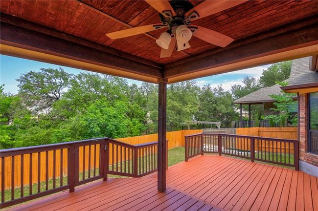 Deck featuring a fenced backyard, ceiling fan, and view of scattered trees | Image 29