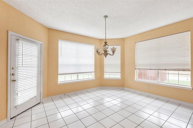 Unfurnished dining area featuring baseboards, an inviting chandelier, a textured ceiling, and a healthy amount of sunlight | Image 4