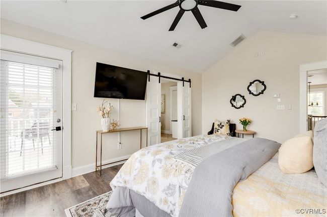 Bedroom featuring visible vents, a barn door, wood finished floors, and vaulted ceiling | Image 37