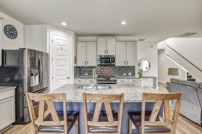 Kitchen featuring appliances with stainless steel finishes, light stone countertops, light wood finished floors, backsplash, and recessed lighting | Image 12