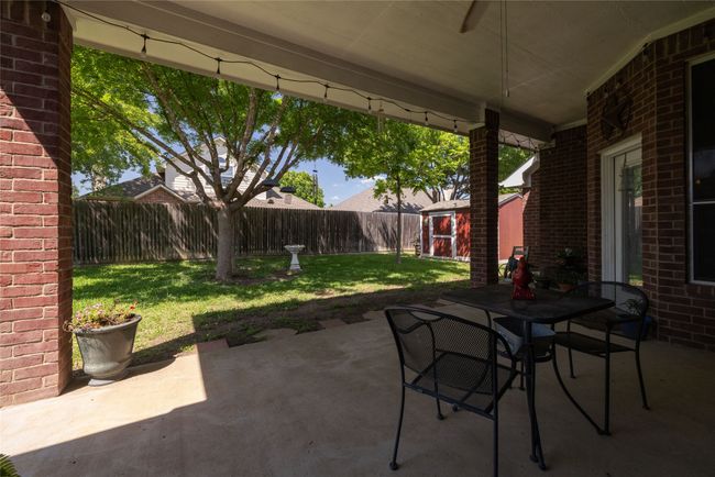 View of patio with a fenced backyard, an outdoor structure, a storage shed, and outdoor dining area | Image 32