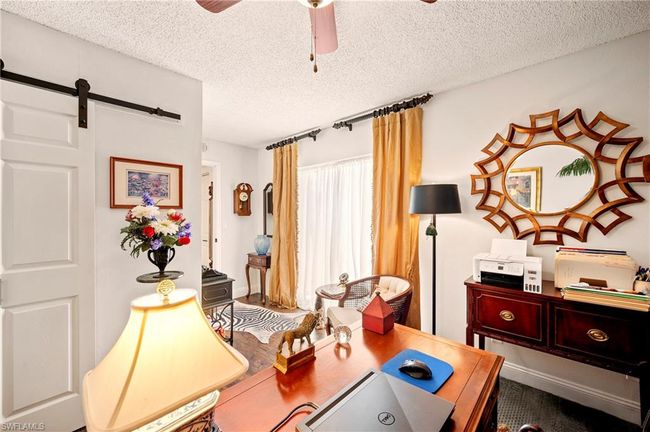 Office space with a textured ceiling, ceiling fan, and a barn door | Image 21