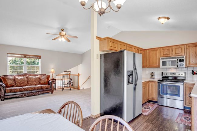Kitchen featuring stainless steel appliances, lofted ceiling, light countertops, open floor plan, and a ceiling fan | Image 10