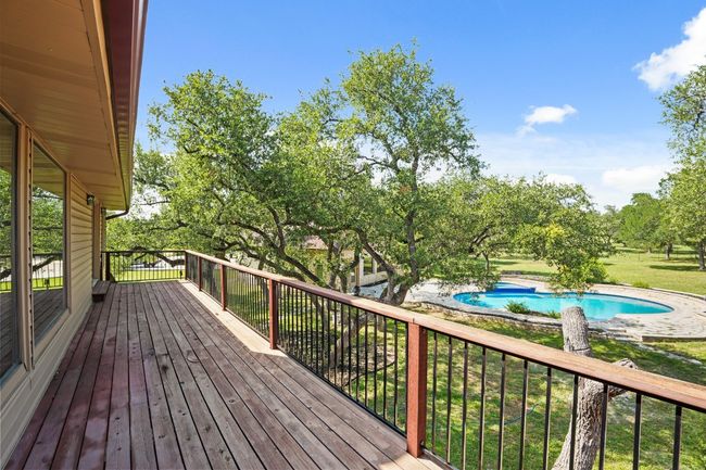 Wooden terrace with an outdoor pool and view of scattered trees with access from primary bedroom and game room | Image 10