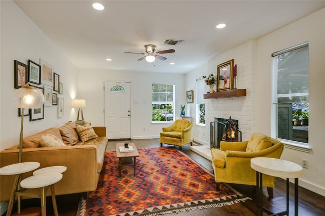 Cozy living room with hardwood flooring, ample lighting, and a brick fireplace. | Image 5