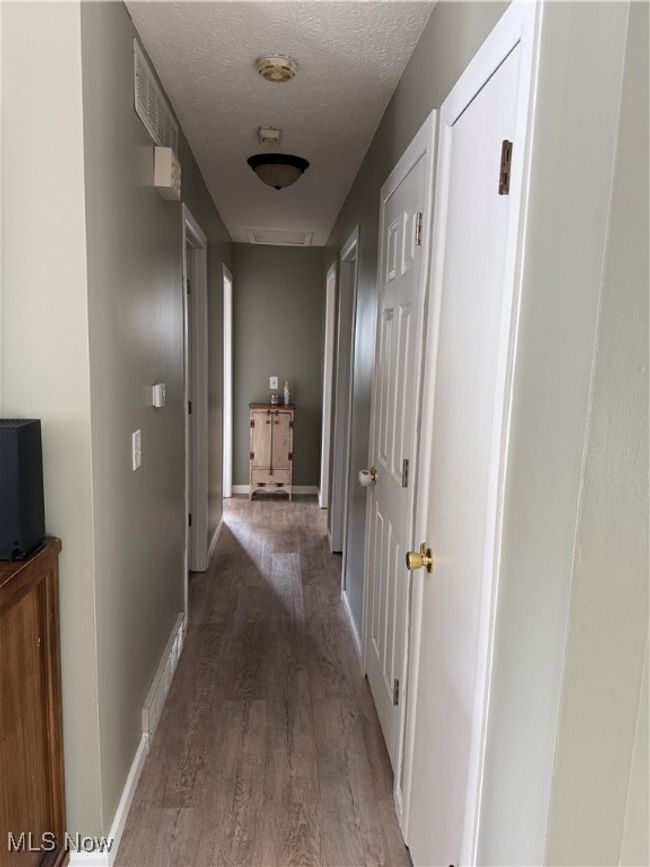Corridor with visible vents, baseboards, wood finished floors, and a textured ceiling | Image 7