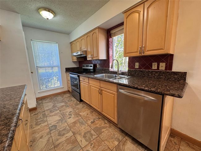Kitchen featuring stainless steel appliances, backsplash, under cabinet range hood, a textured ceiling, and light brown cabinets | Image 6