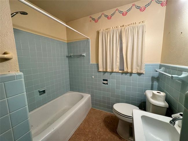 Full bathroom featuring tile walls, toilet, tiled shower / bath combo, tile floors, and vanity | Image 30