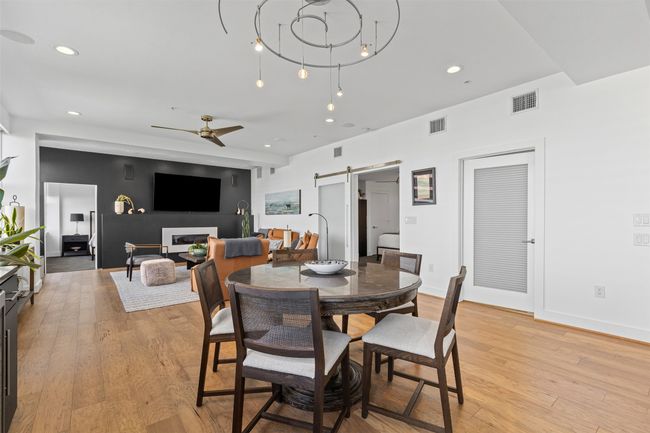 Dining area with a barn door, recessed lighting, visible vents, light wood-style floors, and ceiling fan | Image 9