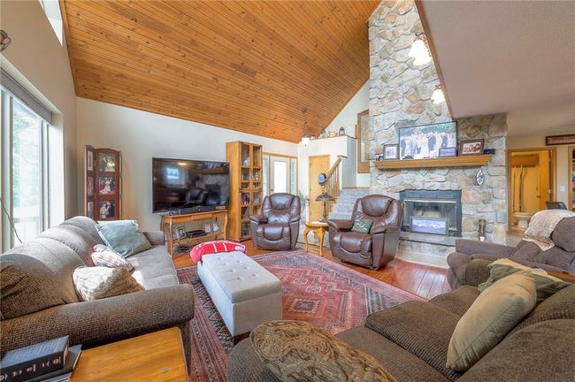 Living room with high vaulted ceiling, a stone fireplace, wood-type flooring, plenty of natural light, and wood ceiling | Image 5